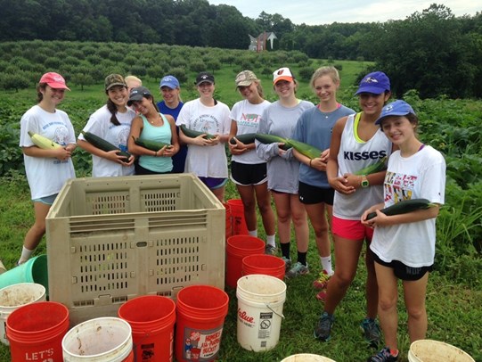 NDP student volunteers holding the zucchini that they harvested at First Fruits Farm.